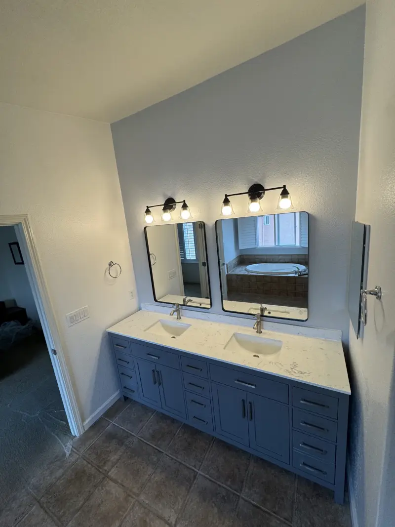 Double-sink blue vanity with round mirrors and black light fixtures