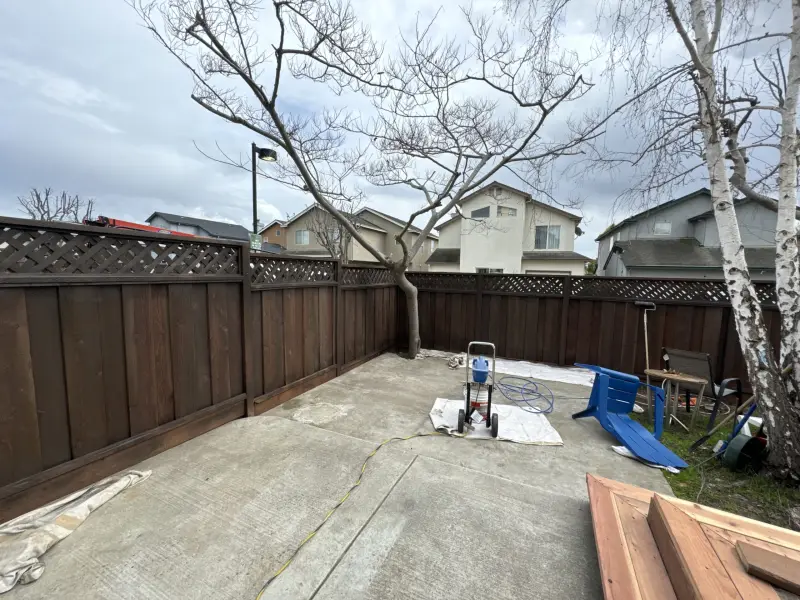 Backyard enclosed by a dark-stained wood privacy fence with a lattice top