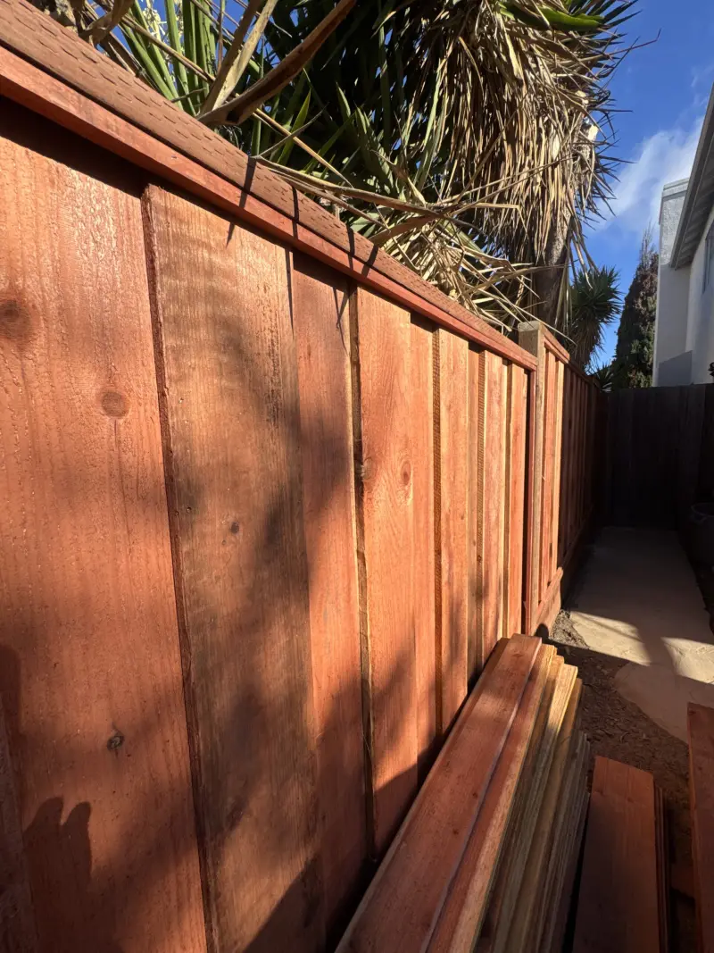 Stained wood privacy fence with a cap rail along a side yard