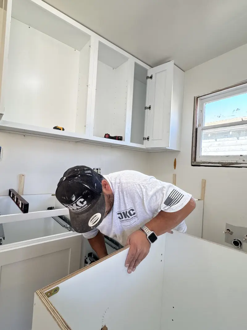 JKC Construction installer setting a new base cabinet