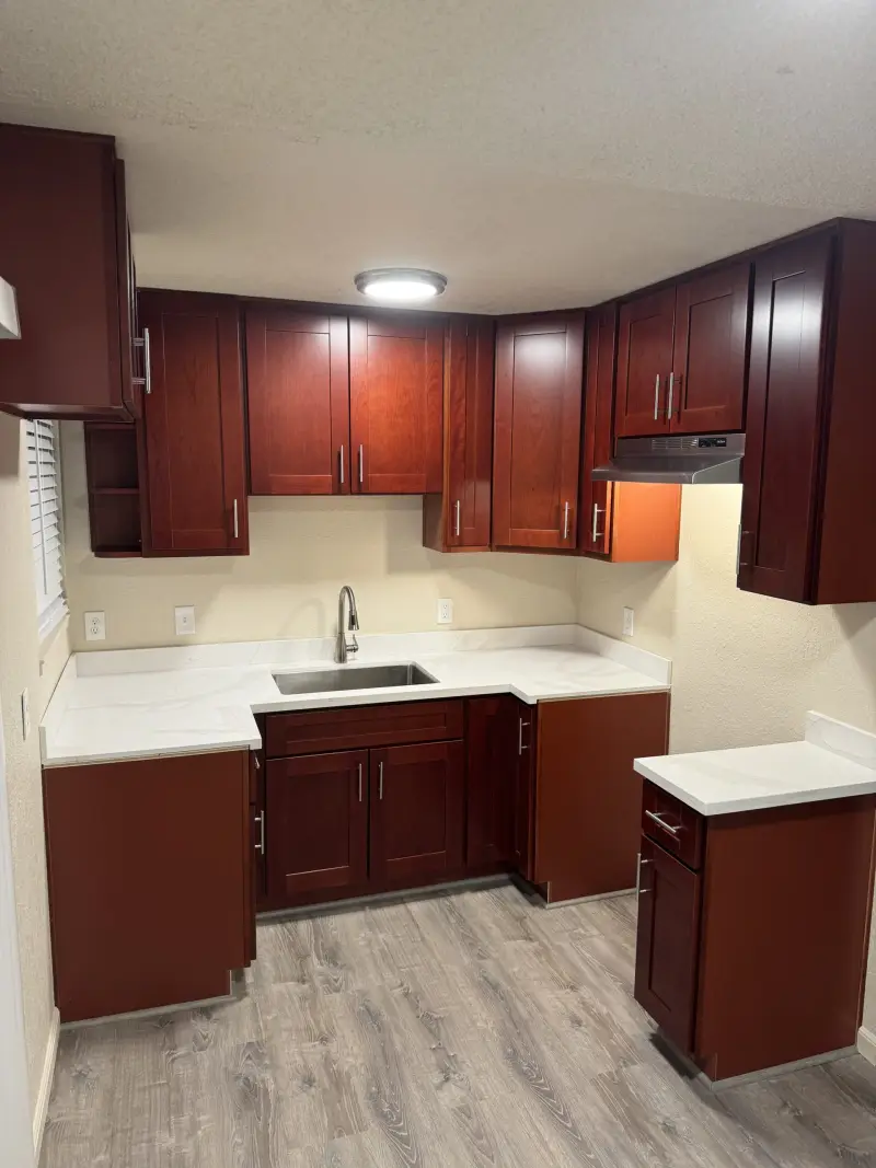 Kitchen remodel with cherry-stained cabinets, white countertops and an undermount sink