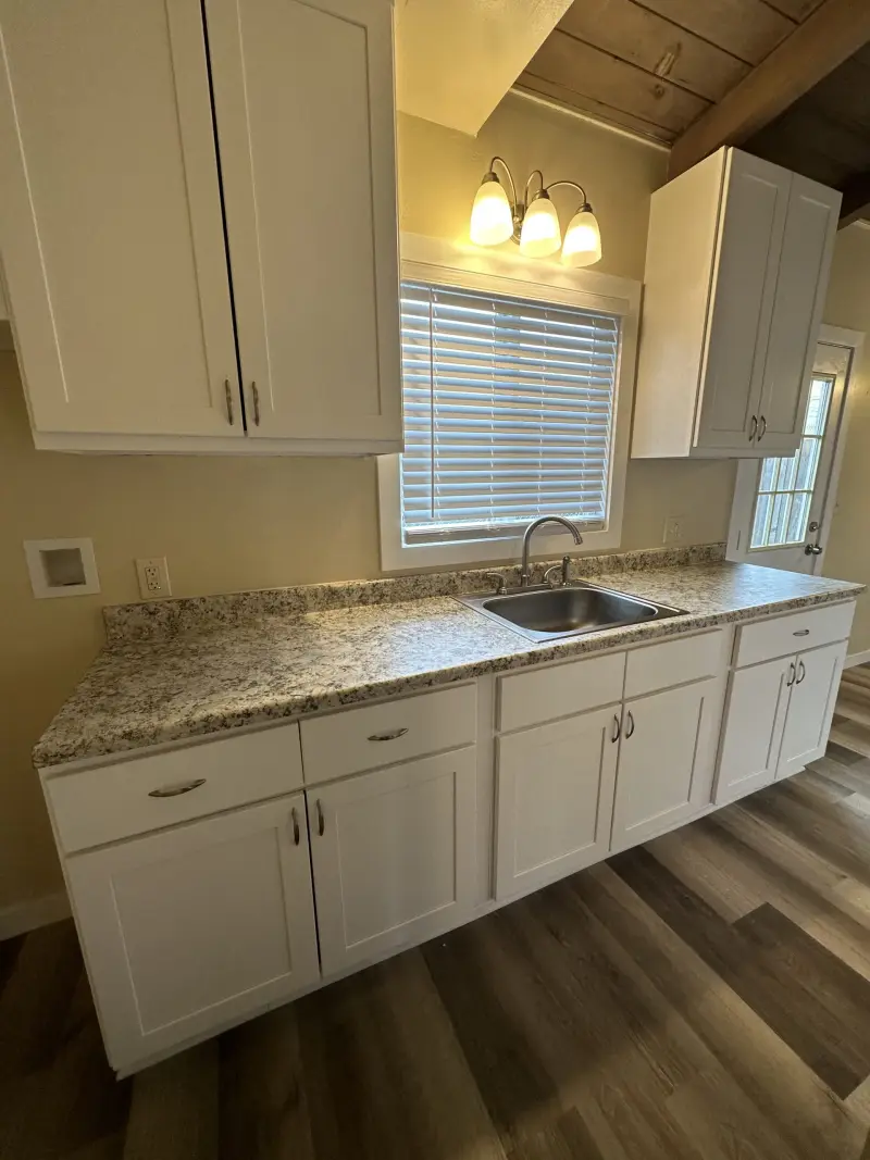 Kitchen with white cabinets, granite countertops and new lighting over the sink