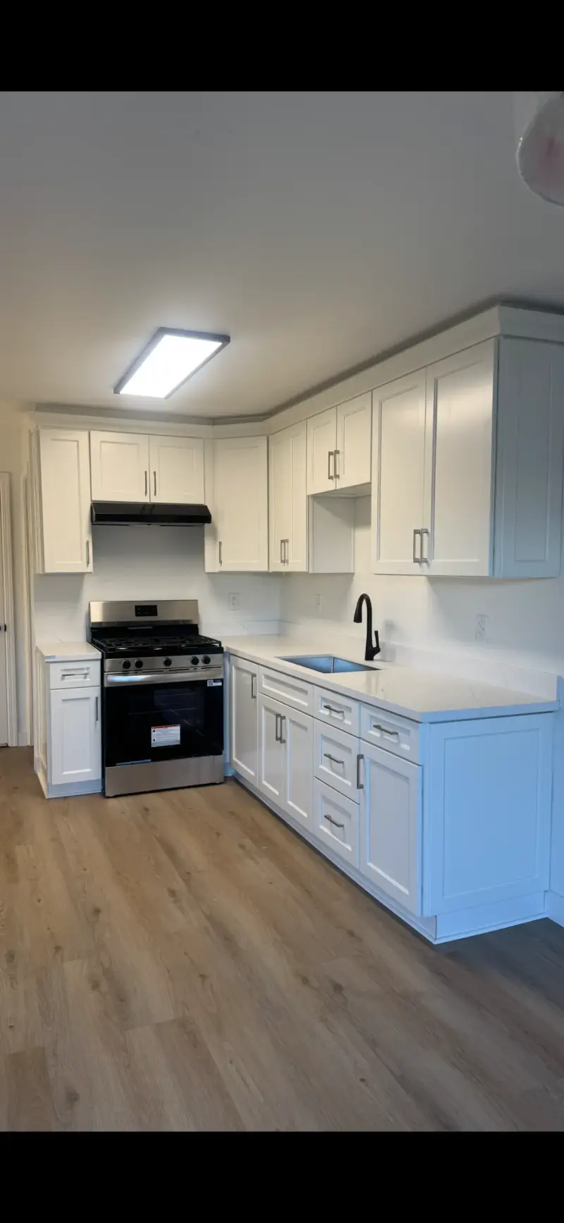 White shaker kitchen cabinets with quartz countertops and a stainless gas range