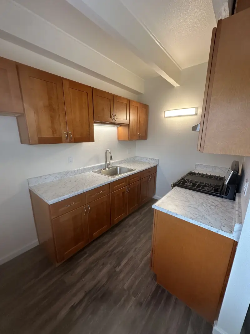 Kitchen with wood-tone cabinets, light stone countertops and under-cabinet lighting