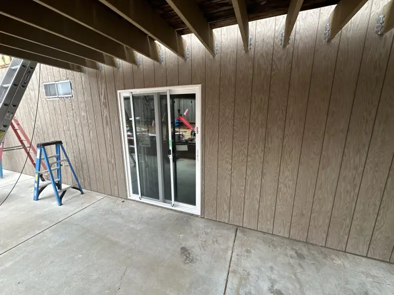 Sliding patio door installed in a wall of vertical panel siding