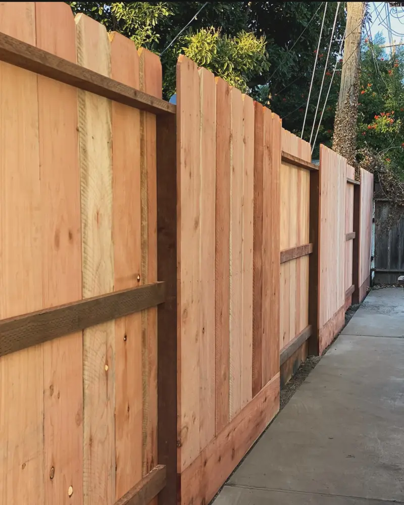New redwood fence boards with a horizontal rail along a side yard