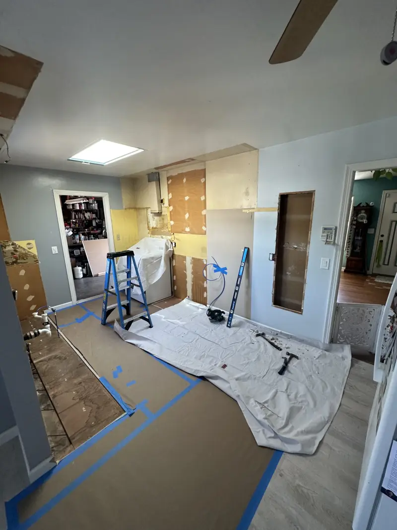 Kitchen remodel in progress with floors protected and cabinets removed
