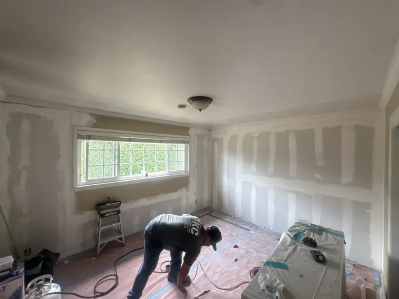 JKC crew member working in a room with freshly patched drywall