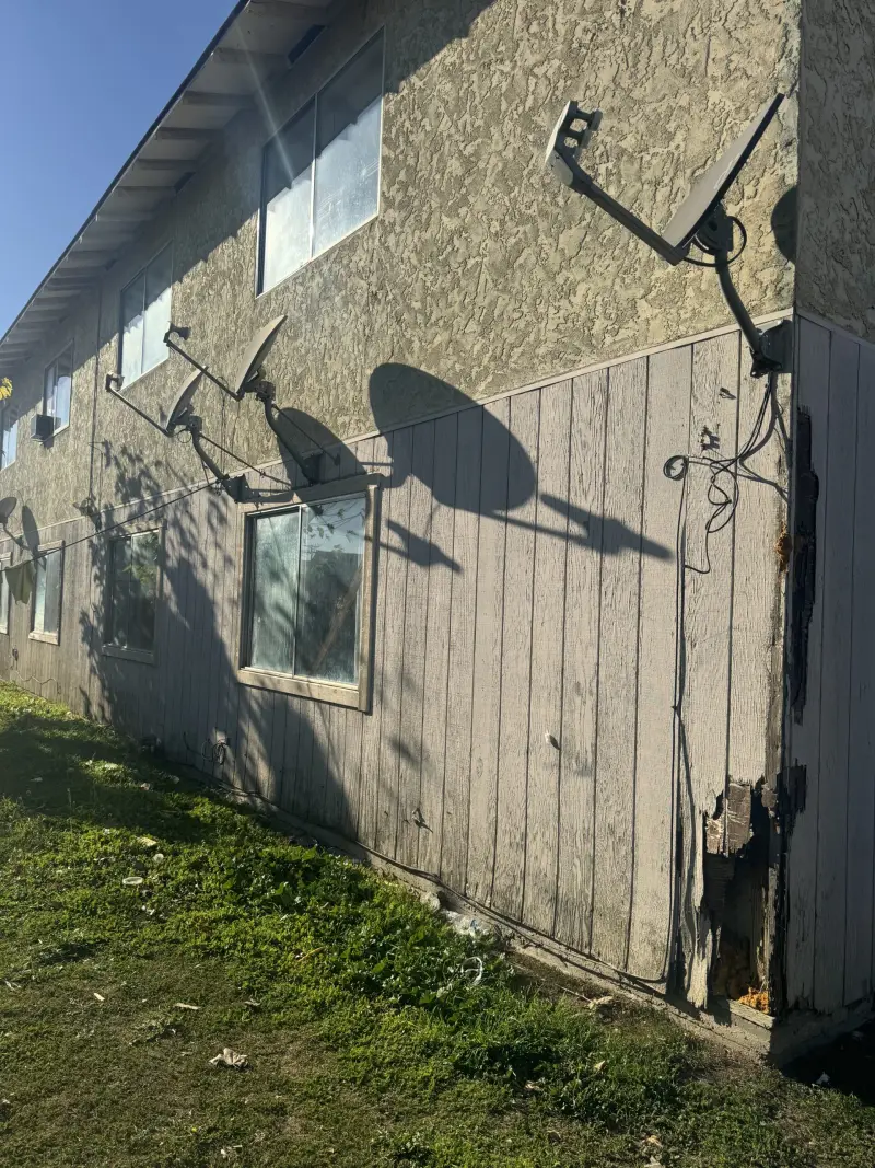 Weathered panel siding with rot at the base, before replacement