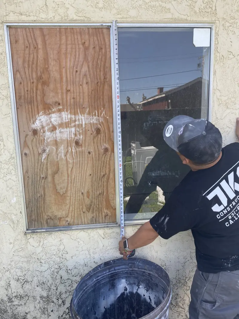 JKC crew member measuring a window opening for a replacement window
